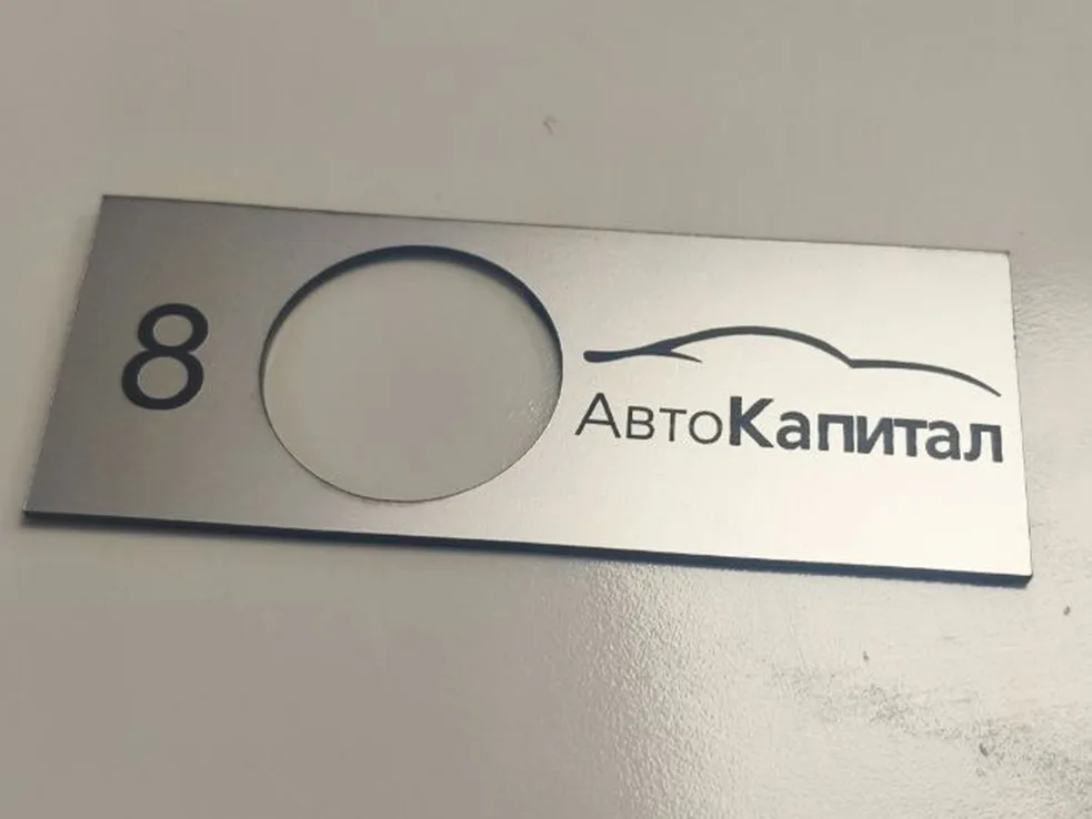 Прямоугольная металлическая пластина с круглым отверстием и нанесённым текстом